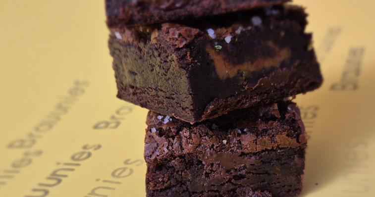 Caixa aberta com brownies artesanais feitos com chocolate belga sobre mesa de madeira 