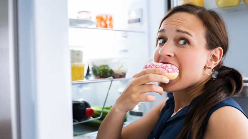 Mujer ansiosa frente a la nevera pensando en comer por ansiedad