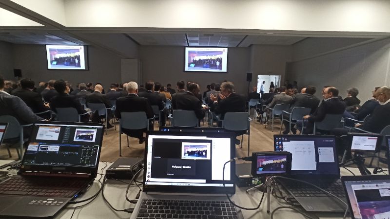 Estúdio moderno com equipamentos audiovisuais e equipe técnica preparando transmissão ao vivo de evento corporativo 