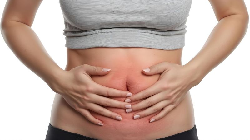 Mulher segurando a barriga com expressão de desconforto, representando inchaço abdominal
