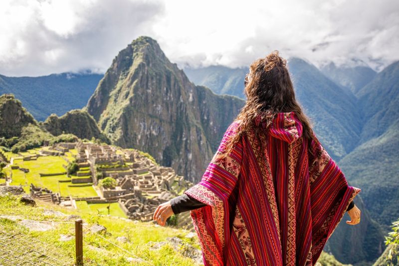 Vista panorâmica das ruínas de Machupicchu com montanhas ao fundo sob céu azul 