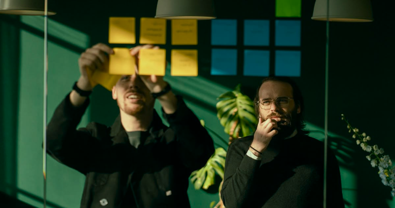 Dois profissionais analisando ideias e organizando post-its em uma sessão estratégica, refletindo colaboração, foco e planejamento em ambiente de trabalho criativo