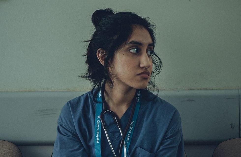 Ilustração corporativa flat de estudante de medicina sentado em mesa com livros e tablet, cabeça apoiada na mão, ambiente calmo com plantas e lâmpada de mesa 