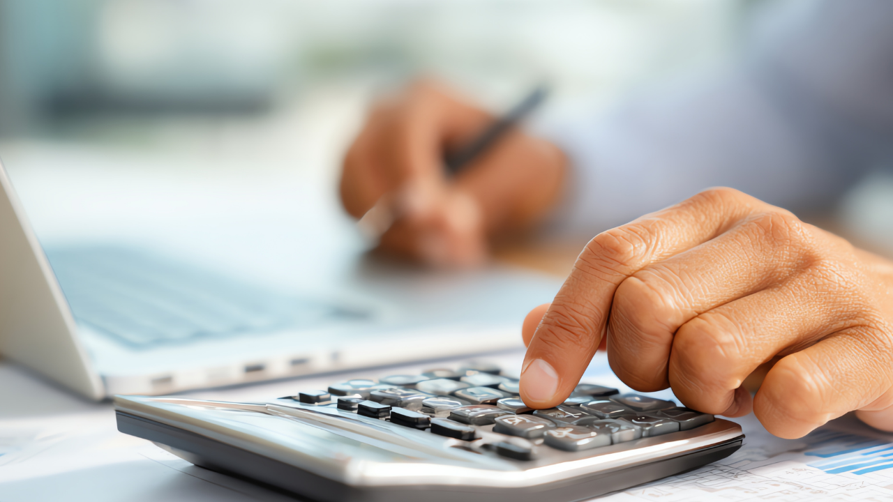 Dona de loja de roupas calculando markup e margem de lucro em frente ao estoque 