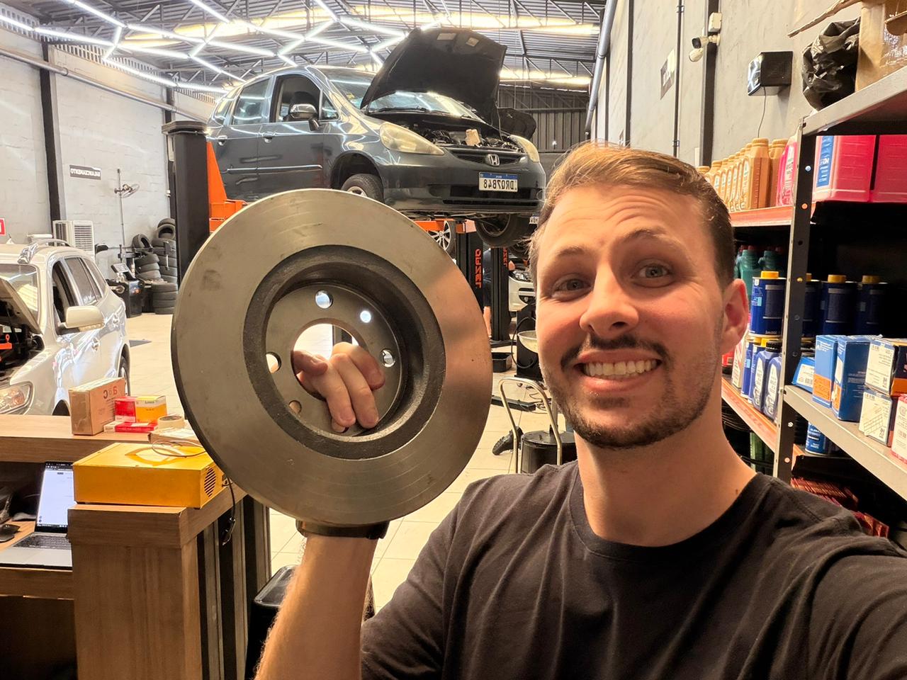 Mecânico examinando de perto o disco e a pinça de freio de um carro em oficina moderna 