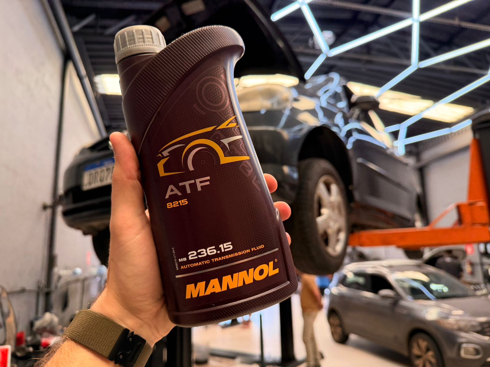 Seleção de frascos de fluido de câmbio Mannol ao lado de componente de transmissão aberta. 