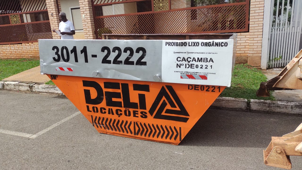 Caçamba de entulho organizada em área de condomínio com resíduos separados 