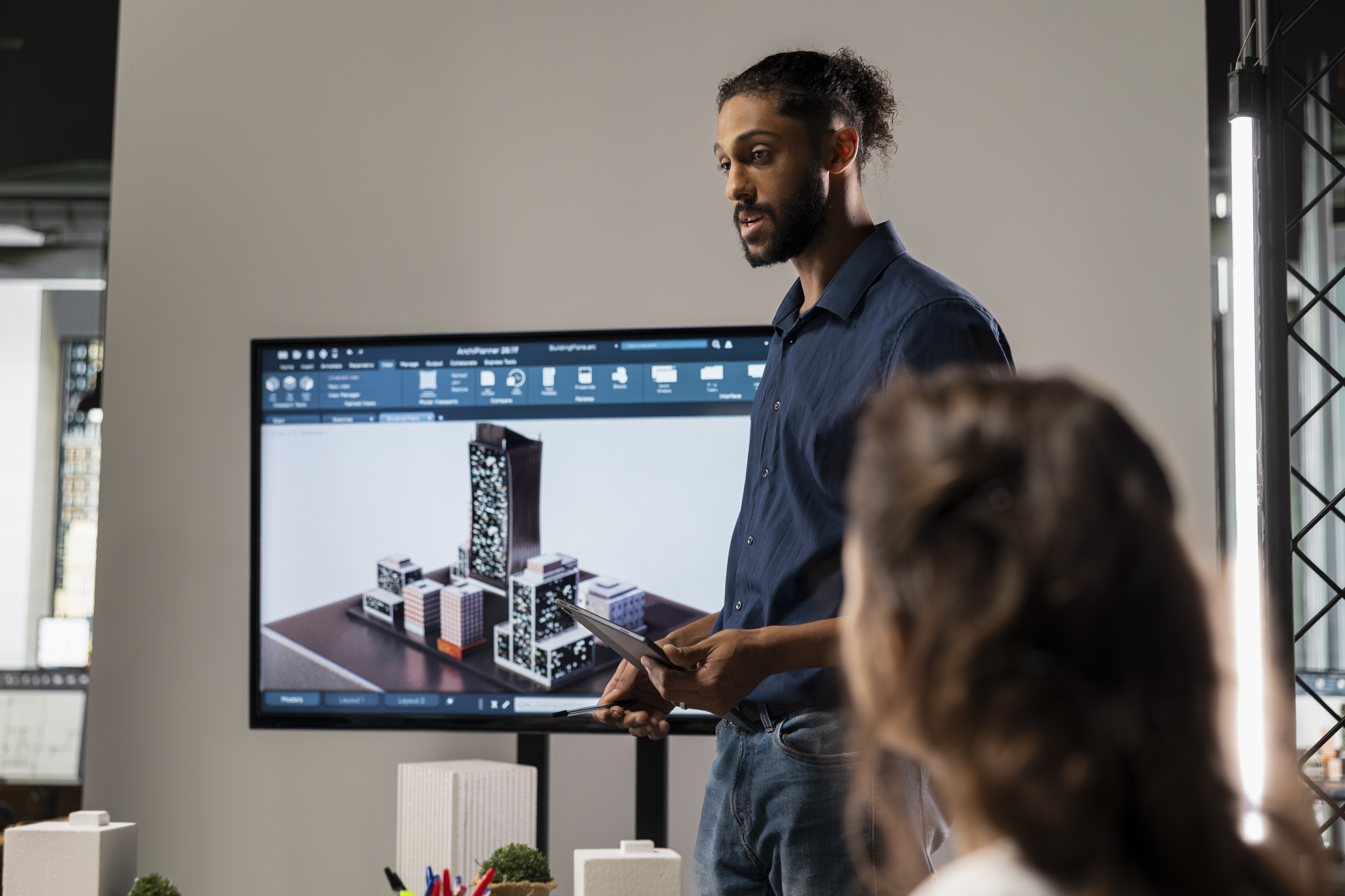 Engenheiros analisando modelo BIM 3D de construção civil em tela grande 