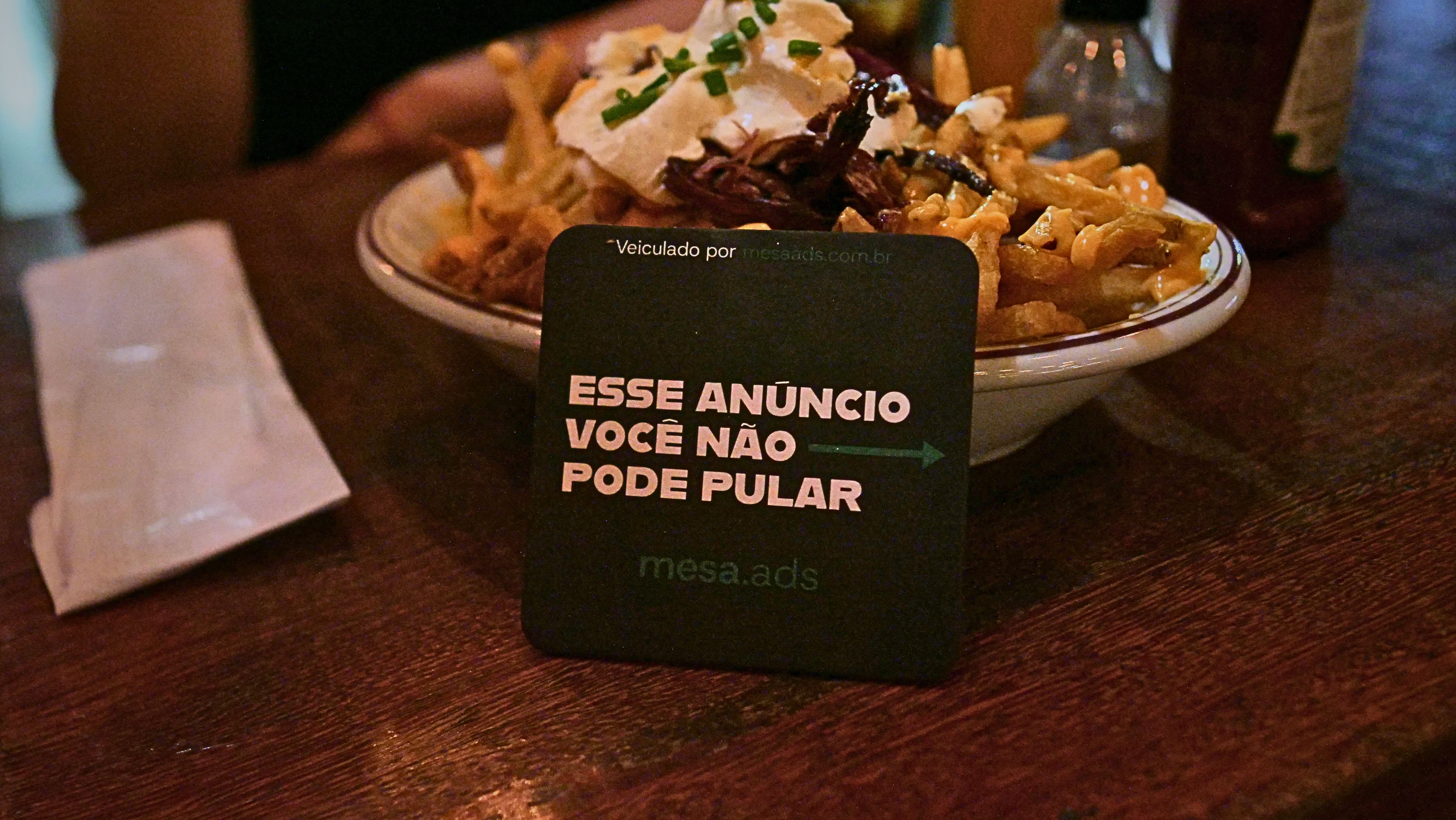 Painel luminoso de OOH em rua movimentada de Manaus visto de dentro de um bar à noite 